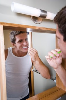 man_brushing_teeth_in_mirror